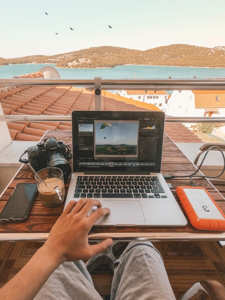 Mudar para a Costa de Prata de Portugal, o guia completo para americanos 3 Pessoa a segurar um MacBook Pro ao lado de um power bank laranja